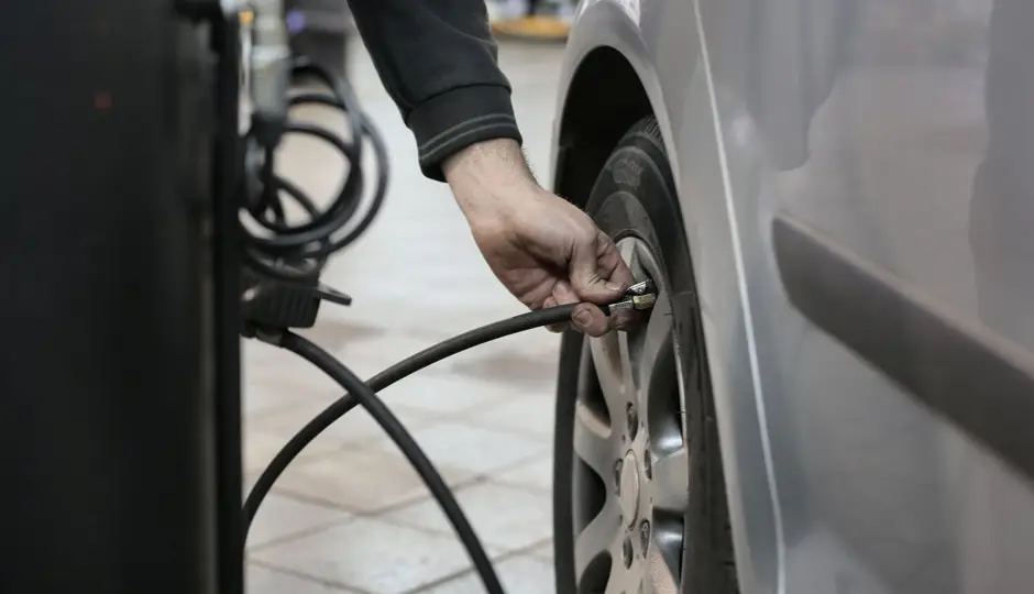Gonfleur pneu voiture portable avec manomètre numérique posé près d'une roue